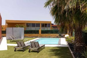 basen z dwoma krzesłami i dom w obiekcie Villa Vulcano by Calima Villas w mieście Costa de Antigua