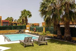 basen z dwoma krzesłami i palmą w obiekcie Villa Vulcano by Calima Villas w mieście Costa de Antigua