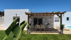 patio z krzesłami i drewnianą pergolą w obiekcie PALAPA GARDEN alojamientos, piscina privada y cerca del mar w mieście Chiclana de la Frontera