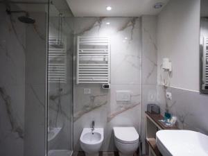 a bathroom with a shower and a toilet and a sink at Hotel Rex in Livorno