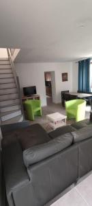 sala de estar con sofá de cuero y sillas verdes en Gite rue Pasteur en Is-sur-Tille