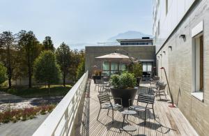 a deck with chairs and an umbrella on a building at Okko Hotels Grenoble Jardin Hoche in Grenoble