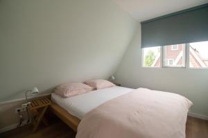 a bedroom with a bed with white sheets and pink pillows at Hermans huisje: het mooiste uitzicht van Twente? in Haaksbergen