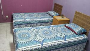 Cette chambre comprend 2 lits avec des draps bleus et blancs. dans l'établissement RUMAH INAP BANDAR PERDANA, à Sungai Petani