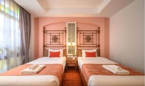 two beds in a room with a window at WOO Gallery & Boutique hotel in Phuket