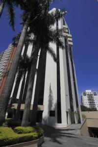 a building with palm trees in front of it at Bienal Suítes in Sao Paulo
