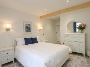 a white bedroom with a large white bed and a mirror at Ferryside in Dartmouth