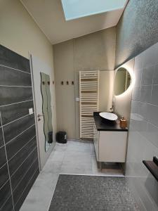 La salle de bains est pourvue d'un lavabo et d'un miroir. dans l'établissement Gîte Le Petit Bambou, à Bressuire