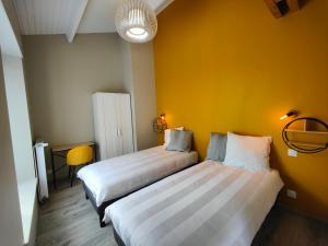 two beds in a room with a yellow wall at Gîte Le Petit Bambou in Bressuire