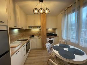 cocina con mesa y cocina con armarios blancos en Апартамент Стил en Chepelare