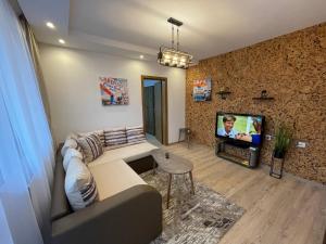 - un salon avec un canapé et une télévision dans l'établissement Апартамент Стил, à Chepelare