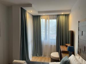 Schlafzimmer mit einem Fenster mit grünen Vorhängen in der Unterkunft Апартамент Стил in Tschepelare