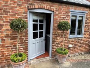 une maison en briques avec une porte et deux plantes en pot dans l'établissement Topiary Barn - Stylish Accommodation in Rutland, à Uppingham