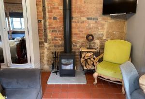 a living room with a yellow chair and a wood stove at Topiary Barn - Stylish Accommodation in Rutland in Uppingham