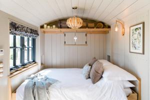Boutique Cornish Shepherd's Hut with Hot Tub في لاونسستون: غرفة نوم بسرير ابيض في غرفة