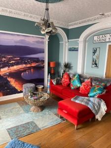 a living room with a red couch and a red chair at Beachfront Boutique Seafront APARTMENT in Aberystwyth