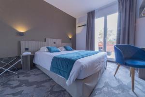 - une chambre avec un grand lit et une chaise bleue dans l'établissement The Originals City, Relax'Otel & Spa, Le Barcarès, au Barcarès