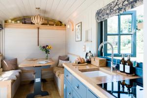 une cuisine avec des placards bleus, un évier et une fenêtre dans l'établissement Boutique Cornish Shepherd's Hut with Hot Tub, à Launceston