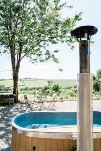 un jacuzzi en un patio con un árbol en Boutique Cornish Shepherd's Hut with Hot Tub en Launceston