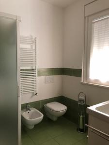 a green and white bathroom with a toilet and a sink at Il Pozzo in San Benedetto del Tronto