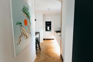 a hallway leading to a kitchen with a painting on the wall at Stan na dan - Chic Home Banja Luka in Banja Luka