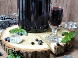 ein Glas Wein und Blaubeeren auf einem Holztisch in der Unterkunft Chata Drevenica in Habovka