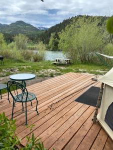 a wooden deck with two chairs and a table on it at Snake River Glamping in Irwin