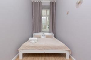 a white bedroom with a bed with a window at Apartments Aleje Jerozolimskie 85 by Renters in Warsaw