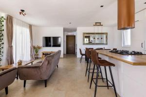 eine Küche und ein Wohnzimmer mit einer Theke und Stühlen in der Unterkunft Casa di Marko-NEW MODERN RUSTIC HOUSE with pool AND SPACIOUS GARDEN! in Privlaka