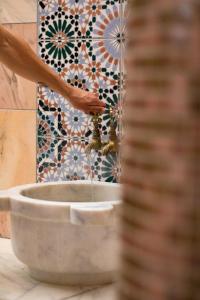 a person drinking water from a fountain in a bathroom at Grande Albergo Delle Rose in Rhodes Town