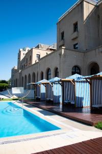 a swimming pool with umbrellas in front of a building at Grande Albergo Delle Rose in Rhodes Town