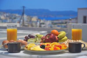 a tray of fruits and vegetables on a table with two glasses of orange juice at Milos village in Triovasálos