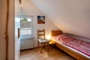 a bedroom with a bed and a chair and a window at Nordsee Ferienwohnung Möwe in Thunum