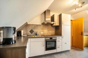 a kitchen with white cabinets and a stove top oven at Nordsee Ferienwohnung Möwe in Thunum +12 photos