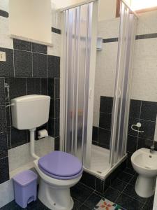 y baño con aseo púrpura y ducha. en Favignana: La porta sul mare en Favignana