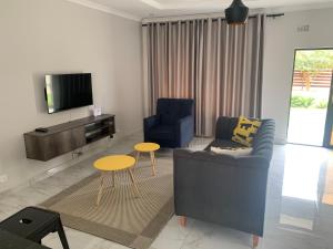 a living room with a couch and chairs and a tv at Greendale Apartments in Lusaka
