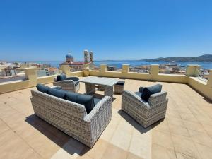 a patio with chairs and a table on a balcony at Hermes Penthouse in Ermoupoli