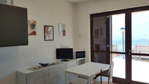 a living room with a table and a desk with a television at La Quiete 08 lake view Apartment By Garda Domus Mea in Tremosine Sul Garda