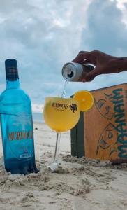 eine Person, die einen Drink in ein Glas am Strand schüttet in der Unterkunft Pousada Maanaim in Ubatuba