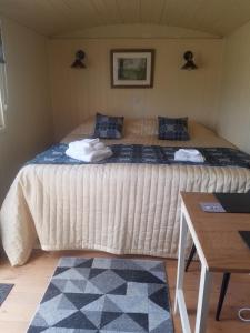 a large bed in a small room with a table at Rhydydefaid Cwt Clyd - Cosy Hut in Bala