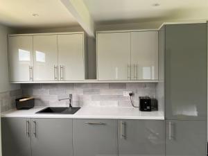 a kitchen with white cabinets and a sink at Shore Times Holiday Chalet Parkdean K75 in Camber