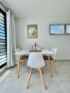 uma sala de jantar com uma mesa branca e cadeiras em Mereani flat brand new condo in the center of Papeete em Papeete