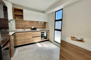 uma cozinha com armários de madeira, um lavatório e uma janela em Mereani flat brand new condo in the center of Papeete em Papeete