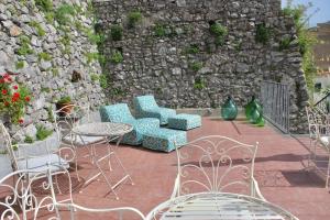 un patio con sillas, mesas y una pared de piedra. en Guest House Malù, en Scala