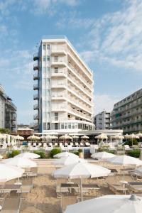 een groot wit gebouw met tafels en parasols bij Hotel Delle Nazioni in Lido di Jesolo