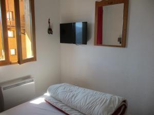 a room with a bed and a television on the wall at Appartement T3 neuf au frais à la montagne in Puy-Saint-Vincent