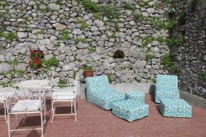 un patio con sillas, mesas y una pared de piedra. en Guest House Malù, en Scala