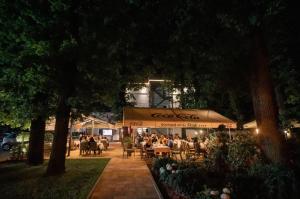 a group of people sitting at tables in a park at night at Hotel Park in Srebrenik