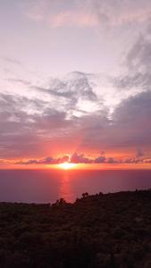 una puesta de sol sobre el agua con el sol en el cielo en South Side en Athánion