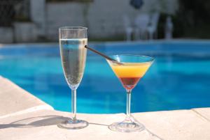 twee glazen zittend op een tafel naast een zwembad bij Chambre d'Hôtes Le Moulin Bertrand in Saint-Martin-de-Ribérac